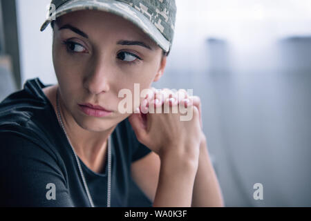 depressed woman in military uniform and cap at home with copy space Stock Photo
