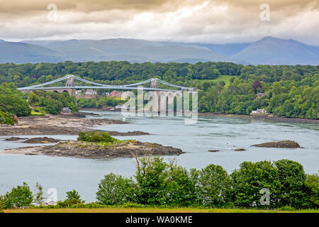 The historic 1826 Menai Bridge by Thomas Telford takes the A5 road over the Menai Straits into Anglesey, with the hills of Snowdonia beyond, Wales, UK Stock Photo