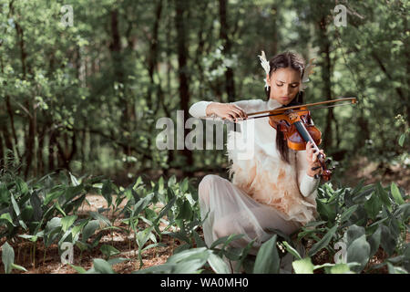 beautiful woman in white swan costume playing on violin Stock Photo