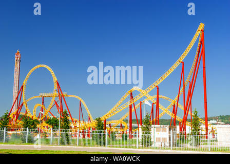 bright red and yellow roller coaster structures in the city’s amusement park Stock Photo