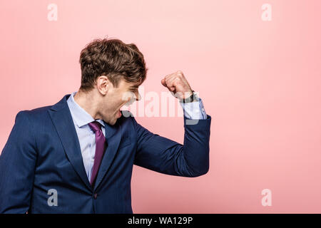 angry businessman showing fist and screaming on pink background Stock Photo