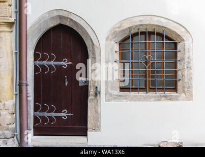 old wooden door and barred glass window in wall of old fortress Saxony Germany Stock Photo