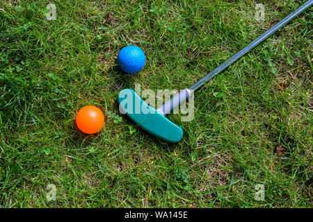 mini golf equipment, balls and a club on the grass, high angle view from above, copy space Stock Photo