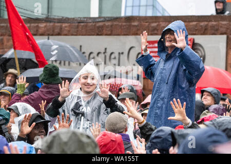 Manchester, UK. 16 August 2019. Protestors and demonstrators commemorate the 200th anniversary of the Peterloo massacre in Manchester. Film director Danny Boyle joined performers marking the event whilst a crowd of thousands braved torrential rain and wind. Credit: Benjamin Wareing/ Alamy Live News Stock Photo