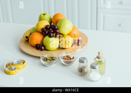 tasty and ripe fruits on plate near measuring tape on table Stock Photo
