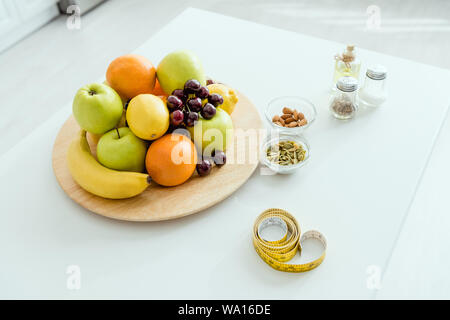 selective focus of tasty and ripe fruits on plate near measuring tape on table Stock Photo