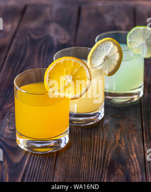 Assortment of citrus juices on the wooden background Stock Photo
