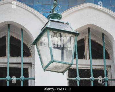 an old street lamp painted the same color as the bars on the street windows Stock Photo