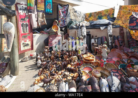 African lady or woman street vendor at her stall with all her products or goods around her holding a wooden bowl to display in Mpumalanga,South Africa Stock Photo