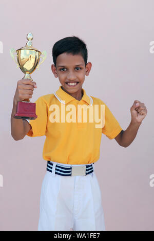 Schoolboy showing a trophy and smiling Stock Photo
