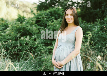 pregnant brunette woman in the park Stock Photo