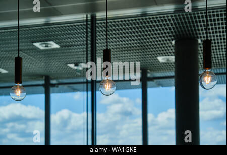 Close-Up Of Illuminated Light Bulbs Hanging In Coffeehouse At Airport Stock Photo