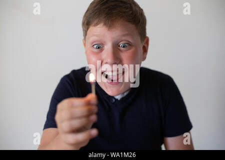 Boy pyromaniac looking to the fire match. Concept of pyromania Stock Photo