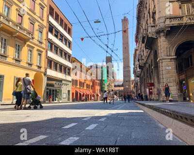 Bologna, Italy - August 2019: People an tourists enjoying the hot Italian summer weather in Via Rizzoli in Bologna city center with view of the two to Stock Photo