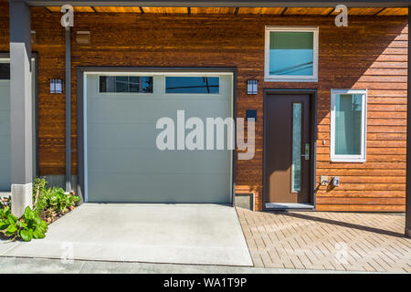 Entrance and garage doors of brand new townhouse with wooden siding wall siding. Stock Photo