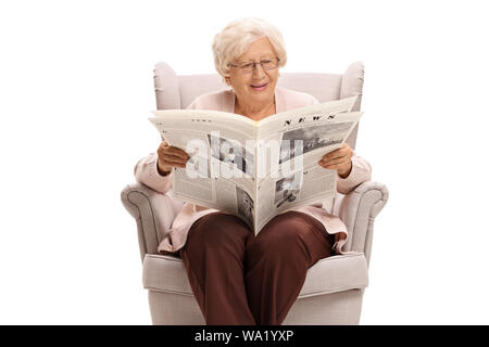 Senior lady sitting in an armchair and reading a newspaper isolated on white background Stock Photo