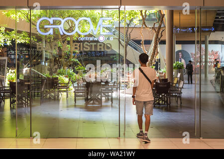 Bangkok, Thailand - May 19, 2019: a man walks in Groove restaurant towards the interior decorated with living trees at Central World shopping mall. Stock Photo