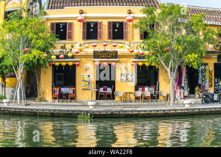 Hoi An, Vietnam - October 28, 2018: sunlit facade of waterfront restaurant decorated with traditional lanterns, located in old town. Fisheye effect. Stock Photo