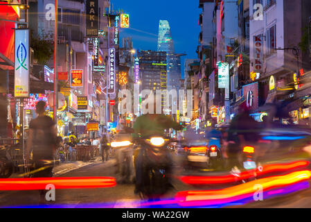 Ho Chi Minh City, Vietnam: Bui Vien Street at night with its neon lights, silhouettes, streaks, and Bitexco Tower in background. Long exposure.