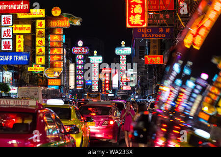 Bangkok - June 13, 2019: night Yaowarat Road, its vibrant neon signboards, street traffic and blurry reflection of the scene on a window of a car. Stock Photo