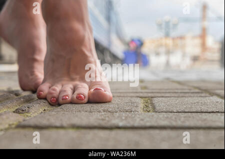 barefoot girl  is standing on the railway platform next to the train Stock Photo