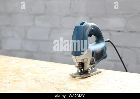 blue-silver electric jigsaw on the osb plate. The process of sawing OSB plywood Stock Photo