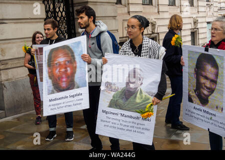 London, UK. 16th Aug 2019. Campaigners with flowers and photographs of the murdered mine workers at the vigil at South Africa House in Trafalgar Square on the 7th anniversary of the deliberately planned massacre of 34 striking miners at Lonmin's Marikana platinum mine by South African police for London mining company Lonmin, whose directors included Cyril Ramaphosa, now President of South Africa. No one has been prosecuted for the murders and they call for justice and for compensation for the workers families. Credit: Peter Marshall/Alamy Live News Stock Photo