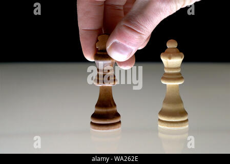 Hand moving a black chess king next to the white queen, as a concept for rivalry, competition, power games. Stock Photo