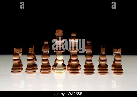 Black chess formation with a single white piece as a concept for undercover operations, infiltration, racial tension, ethnic minorities. Stock Photo