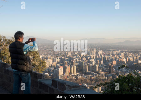 Man takes photos of city below from San Cristobal hill in Santiago, Chile Stock Photo