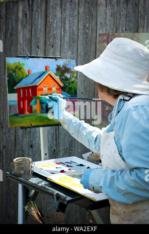 A woman artist paints a picture of a historic building at the Greenfield Village at the Henry Ford Museum in Dearborn, Michigan, USA Stock Photo