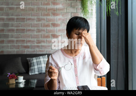 Old woman headache while using smartphone, healthcare concept Stock Photo