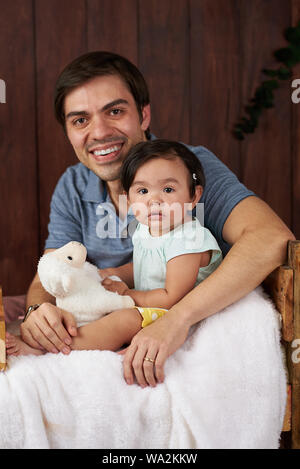 Portrait of smiling dad with daughter in studio background Stock Photo