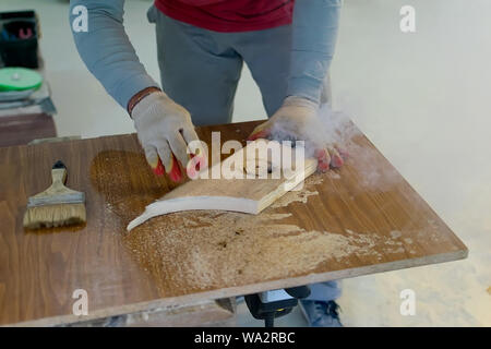 Hands of the master in gloves hold a wooden billet, while working on the milling equipment Stock Photo