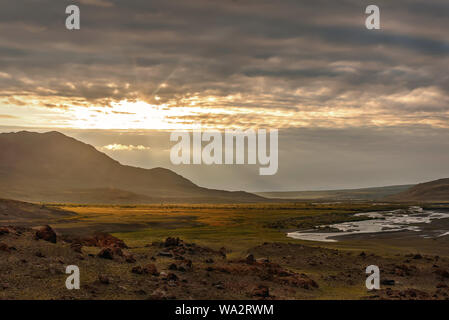 Amazing golden sunrise with mountains and a valley with a winding river in the first rays of sunlight on the background of the beautiful illuminated c Stock Photo