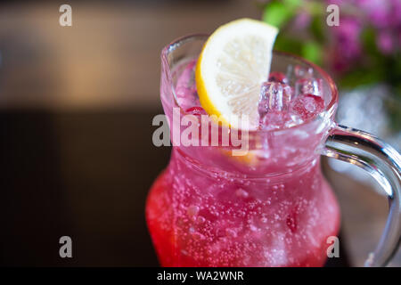 Close up. Summer iced drink with lemon dipping in red juice, with soda for cold drink booster after work out or sun exposure outdoor. Food and drink p Stock Photo