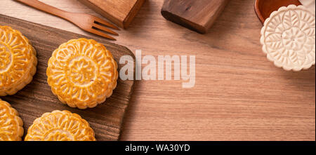 Round shaped fresh baked moon cake pastry - Chinese moonckae for Mid-Autumn Moon Festival on wooden background and serving tray, top view, flat lay. Stock Photo