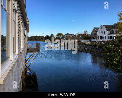 Portsmouth, NH / USA - Oct 17, 2018: Landscape view of waterfront homes, boat, dock and reflections in the water. Side view of Sanders Fish Market. Stock Photo