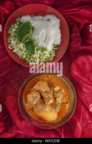 Massaman pork curry served with rice noodles and fresh vegetables . Thai style coconut milk curry Stock Photo