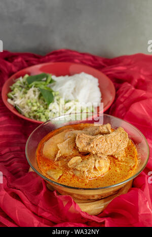 Massaman pork curry served with rice noodles and fresh vegetables . Thai style coconut milk curry Stock Photo