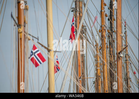 Norwegian flags hanging from the masts of old wooden sailing boats. Stock Photo