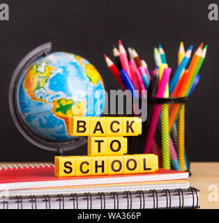 World globe with pencils and text over blackboard Stock Photo