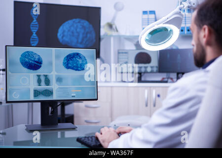 Young medical assistant working on computer in a hospital laboratory. Brain diagnosis. Stock Photo