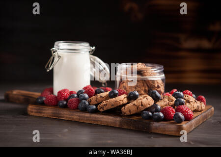 Delicious brown cookies on wooden plate with fresh bluebarries. Organic milk. Stock Photo