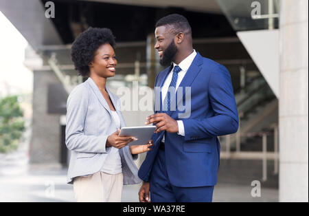 Happy young fellow workers browsing internet on digital tablet outdoors Stock Photo