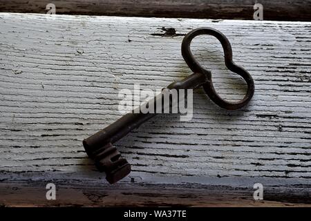 A closeup image of Vintage Antique copper key on old wooden background Stock Photo