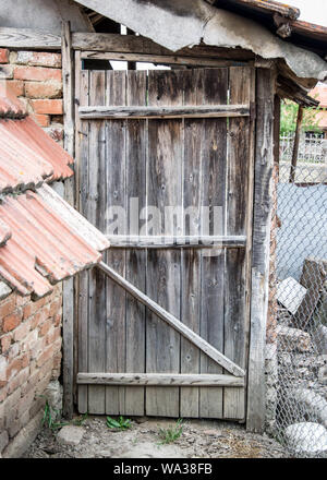 Old rustic wooden door in the backyard, broken door, open or closed door in the garden, timber broken door, rural scenery Stock Photo
