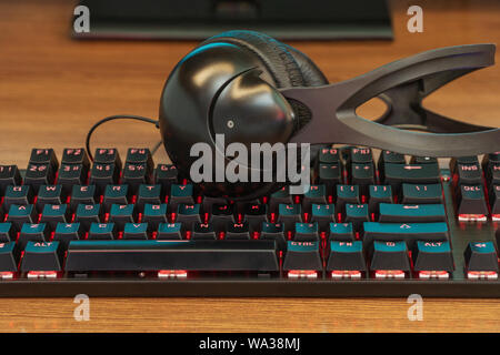 large black headphones on the keyboard with blue backlight Stock Photo