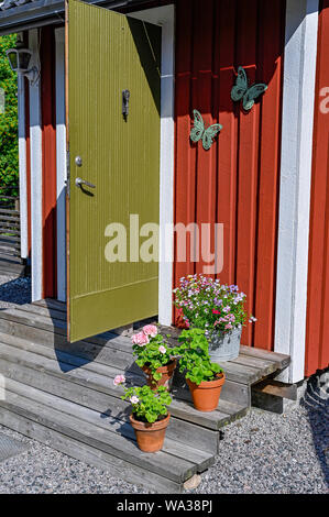 flowers on stairs infront of a red wooden cabin Stock Photo