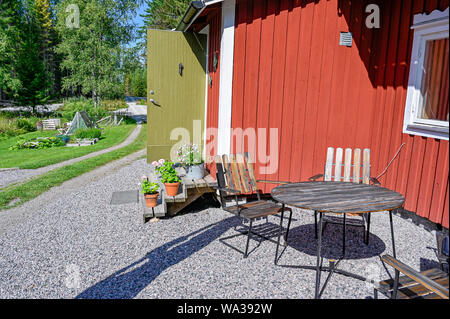 flowers on stairs infront of a red wooden cabin Stock Photo